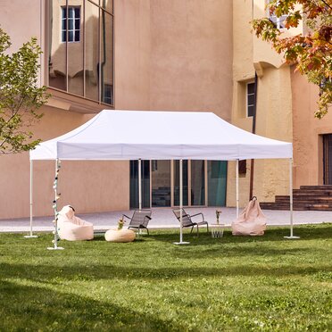 Gazebo Ecotent bianco 6x4m su gairdino davanti alla biblioteca di Bressanone utilizzato outdoor per area relax con puf, tavoli e libri