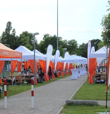 Serie di gazebo per eventi 6x3m bianchi con tende angolari arancioni personlizzati con logo IngDiba e bandiere a goccia bianche per evento all'aperto