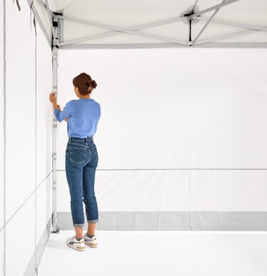 The woman assembles the 2 closed side walls on the folding gazebo.