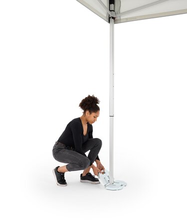 The woman attaches the 28 kg base plate to the folding gazebo.