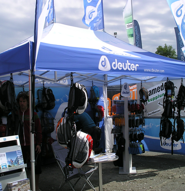 Gazebo blu 4,5x3 Deuter personalizzato con teli laterali e bandiere a goccia pubblicitarie con logo per vendita zaini sportivi durante manifestazione. Ecotent