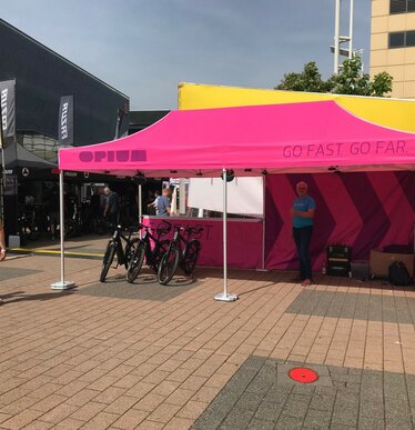 Gazebo pieghevole fuxia 6x3 personalizzato con logo Opium e diversi teli laterali all'Eurobike in Svizzera fa da stand delle biciclette.