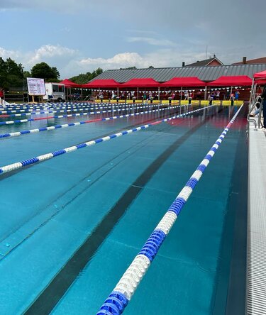 Sei gazebo rossi 8x4 al bordo di una piscina olimpionica esterna