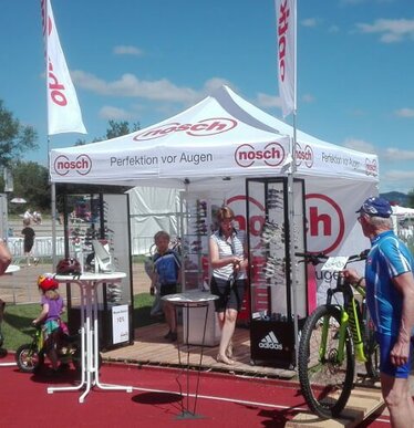 Gazebo 3x3 bianco con telo laterale personalizzato con logo rosso Optik Nosch utilizzato come gazebo espositivo durante una manifestazione sportiva