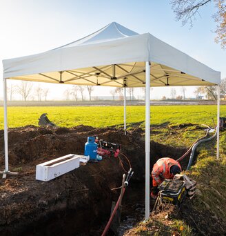 Gazebo bianco 4x2 da lavoro utilizzato per coprire lavoratori e cantiere in un campo lungo il ruscello