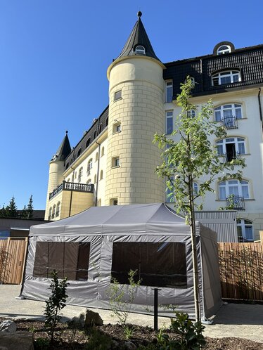 Gazebo pieghevole con teli laterali con finestre panoramiche grigio scuro davanti al castello del sauna hotel SEN