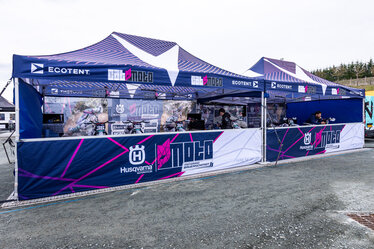 Team Cat Moto Motocross con due gazebo pieghevoli Ecotent nel paddock durante una gara europea.